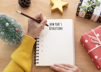 Woman hand writing New year's resolution on note paper in new year day.