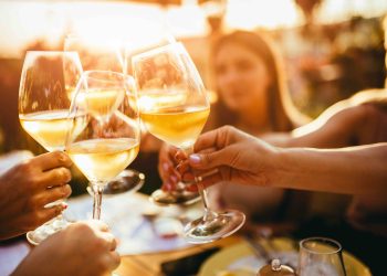 People clinking glasses with wine on the summer terrace of cafe or restaurant