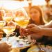 People clinking glasses with wine on the summer terrace of cafe or restaurant