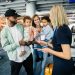 A family with two young children getting ready to board a flight together, letting an airport staff member check their passports and boarding passes at the gate.