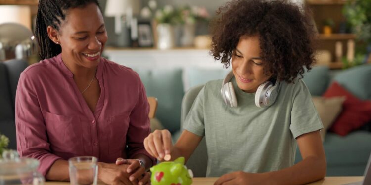 Mother and her teenage son saving money in piggy bank