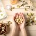 Female hands with macadamia nuts and natural cosmetics on wooden background