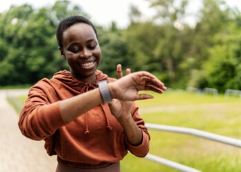 African American jogger getting ready for workout looking at smart watch.