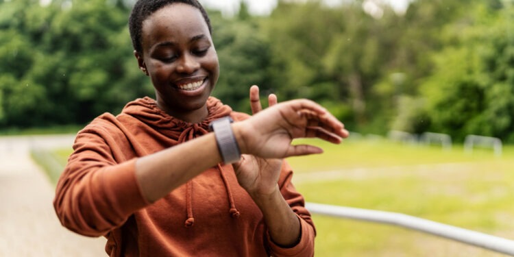 African American jogger getting ready for workout looking at smart watch.