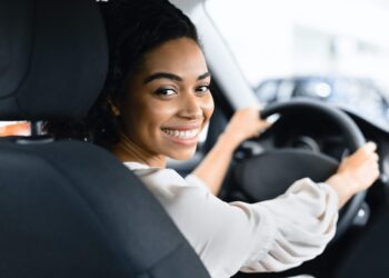 Afro Woman Driver Buying New Car Doing Test Drive Choosing New Auto In Dealership Store. Selective Focus