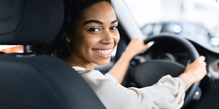 Afro Woman Driver Buying New Car Doing Test Drive Choosing New Auto In Dealership Store. Selective Focus