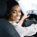 Afro Woman Driver Buying New Car Doing Test Drive Choosing New Auto In Dealership Store. Selective Focus