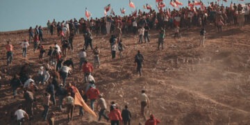 People climb a hill in a crowd waving Chilean flags. (credit: Miguel Soffia)