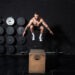 Young strong fit sweaty muscular man with big muscles doing box jump workout in the gym as hardcore cross training