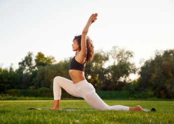 Warrior yoga exercise. Young fitness woman is on the field outdoors.