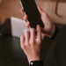 Woman;s hand holding cellphone ready to unlocked it. Girl using telephone near table wit computer in office